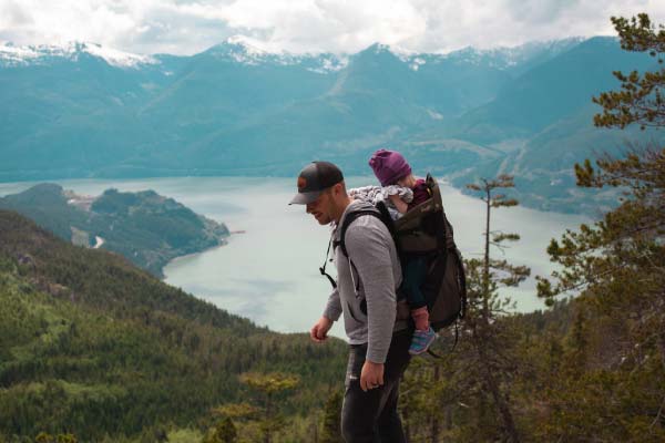 Adulte portant un bébé à la montagne